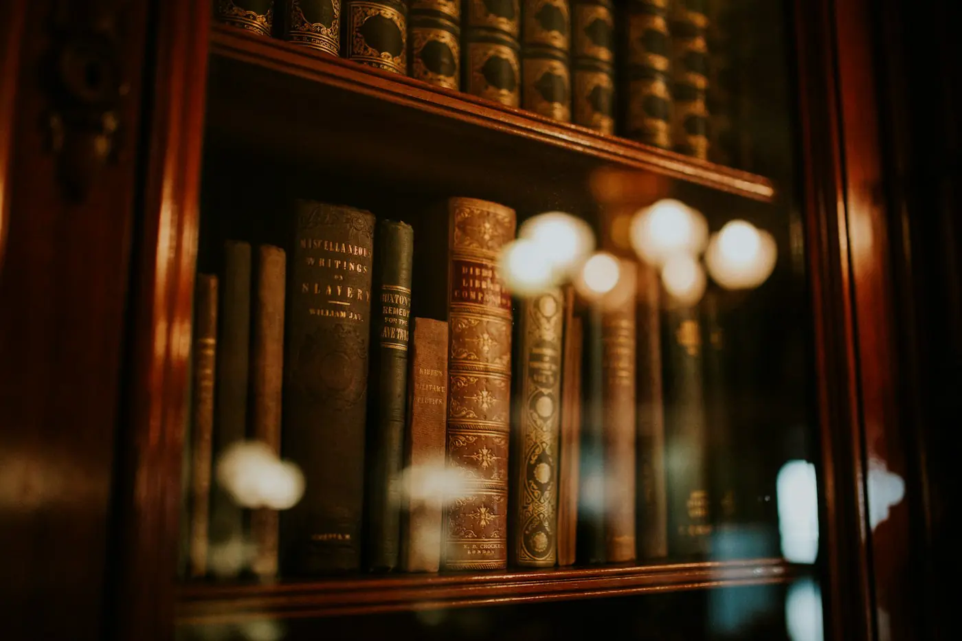 Leather-bound books on a wooden shelf