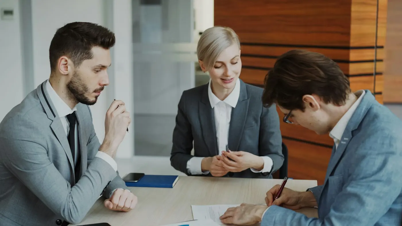 Three colleagues discussing a document at a meeting table