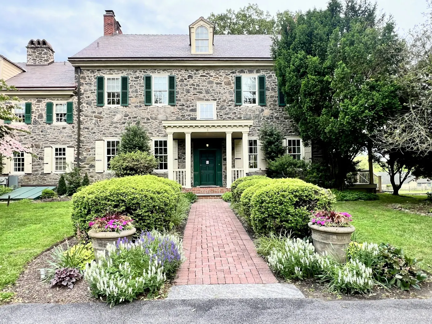 Stone house with a green door and a flower-lined garden path