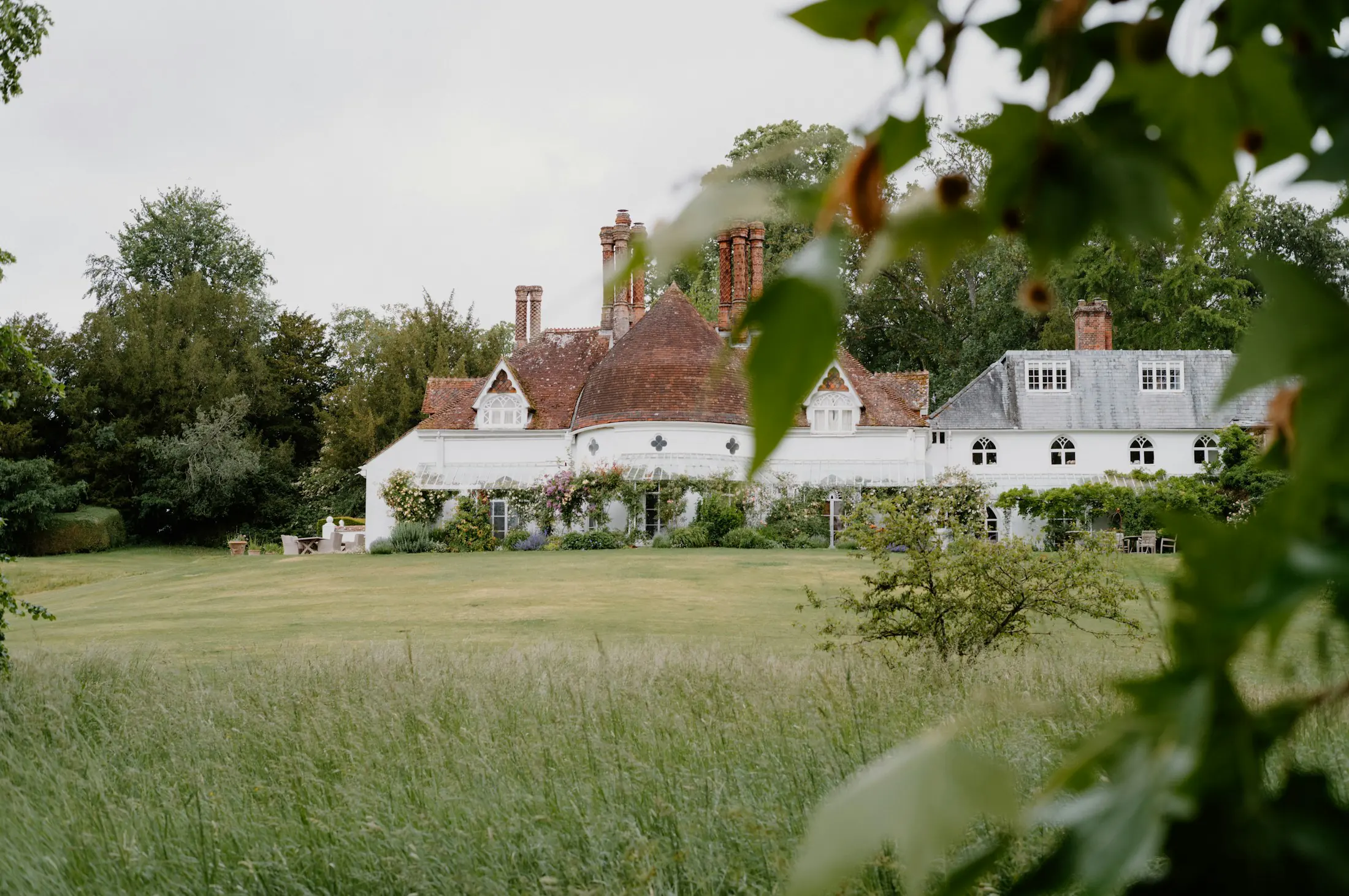 Country house with a long meadow in front, framed by trees