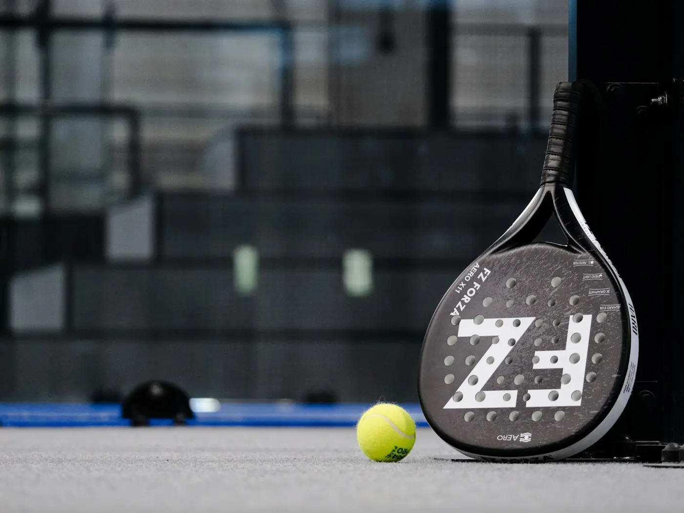 Padel racket and ball resting on a court