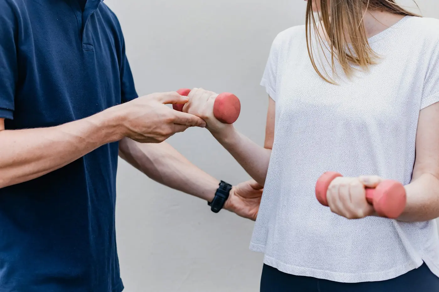Physiotherapist guiding a patient through a strengthening exercise with dumbbells